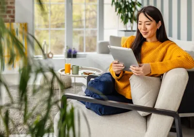 Woman on couch looking at tablet. 